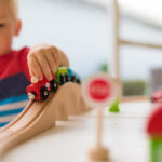 Little boy playing with wooden toy train.